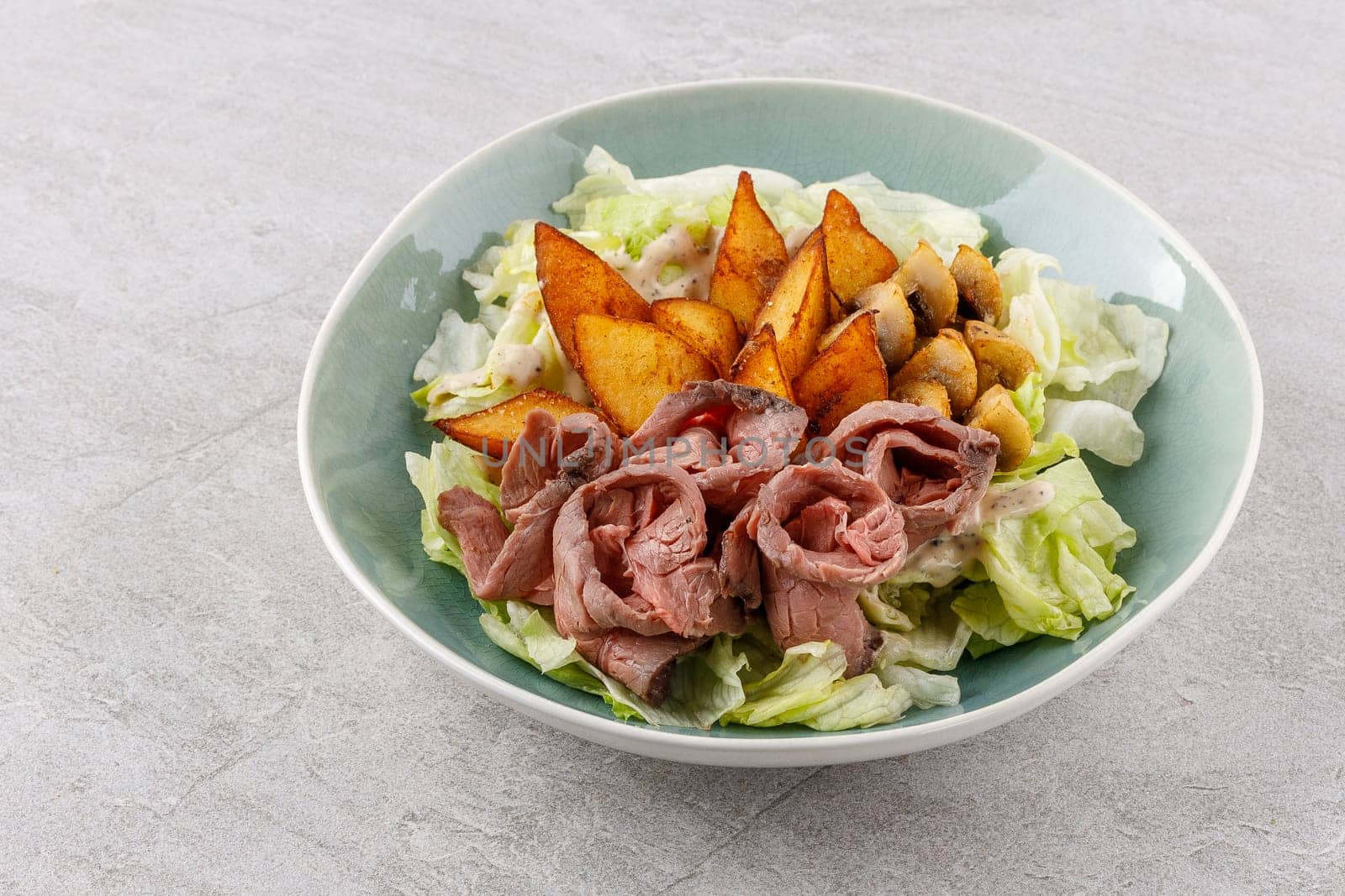 Salad with roast beef and potatoes on a stone background, studio food photo