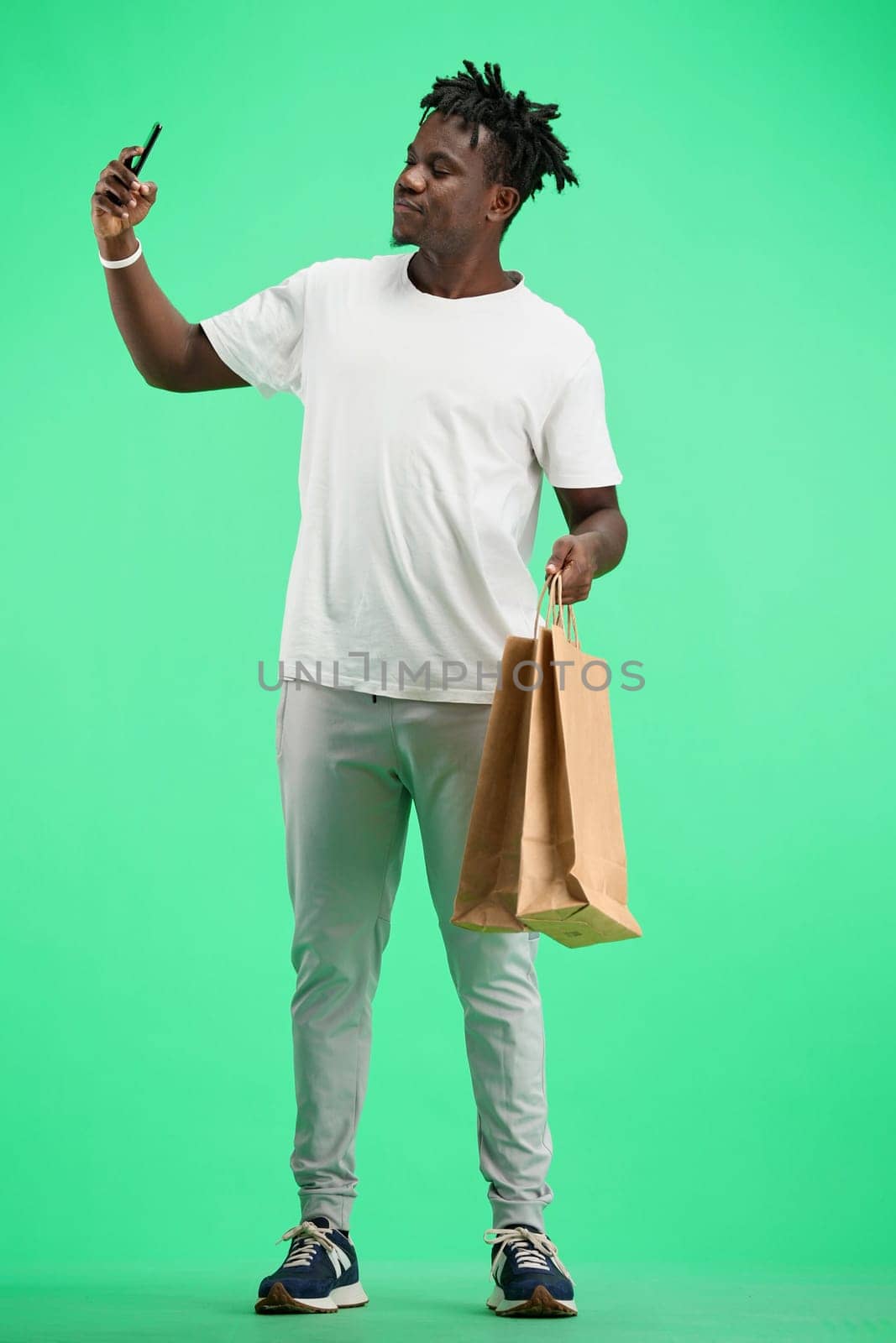 A man, full-length, on a green background, with bags.