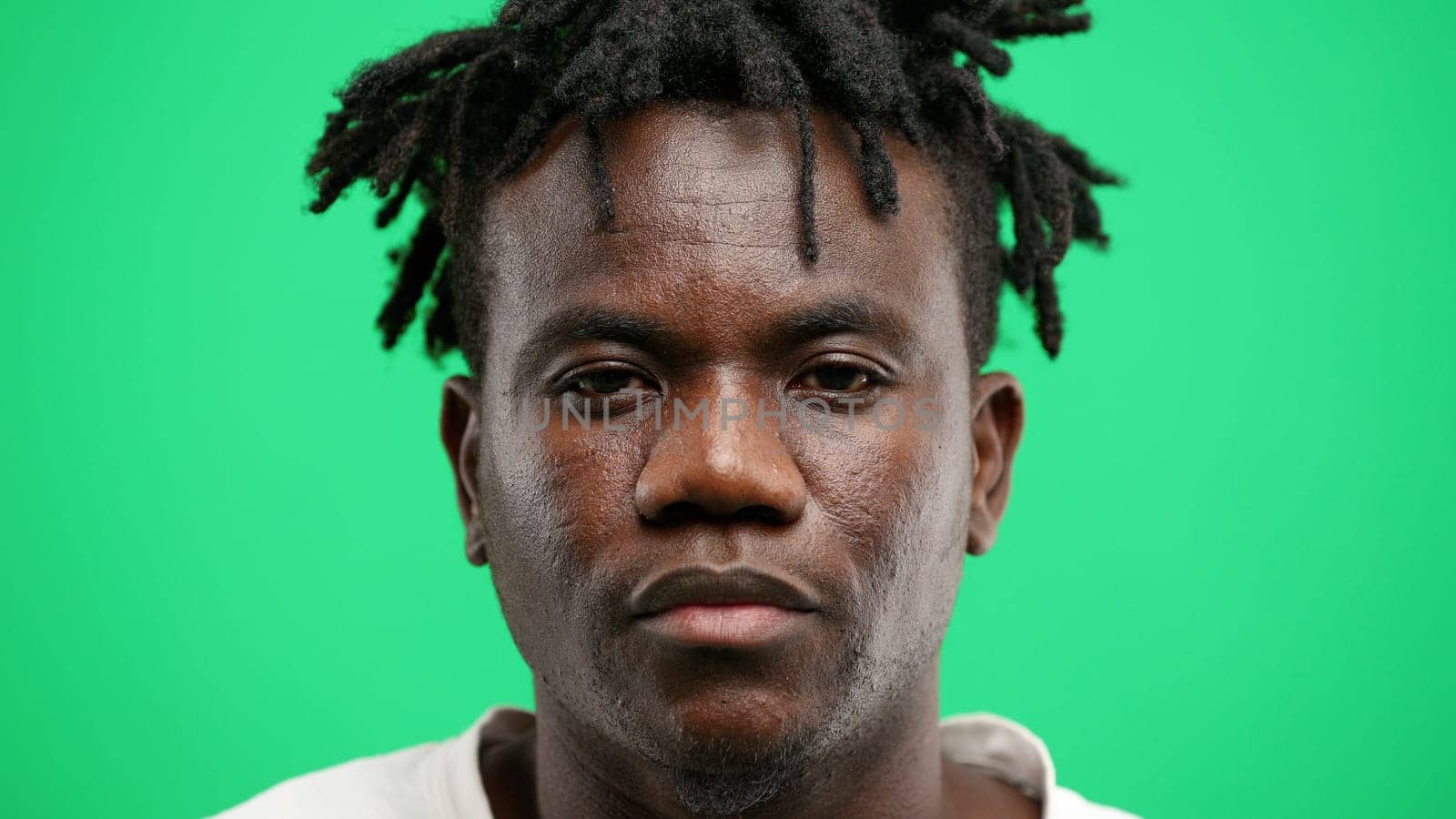 Man's face, close-up, on a green background.