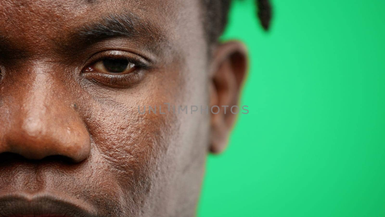 Man's face, close-up, on a green background.