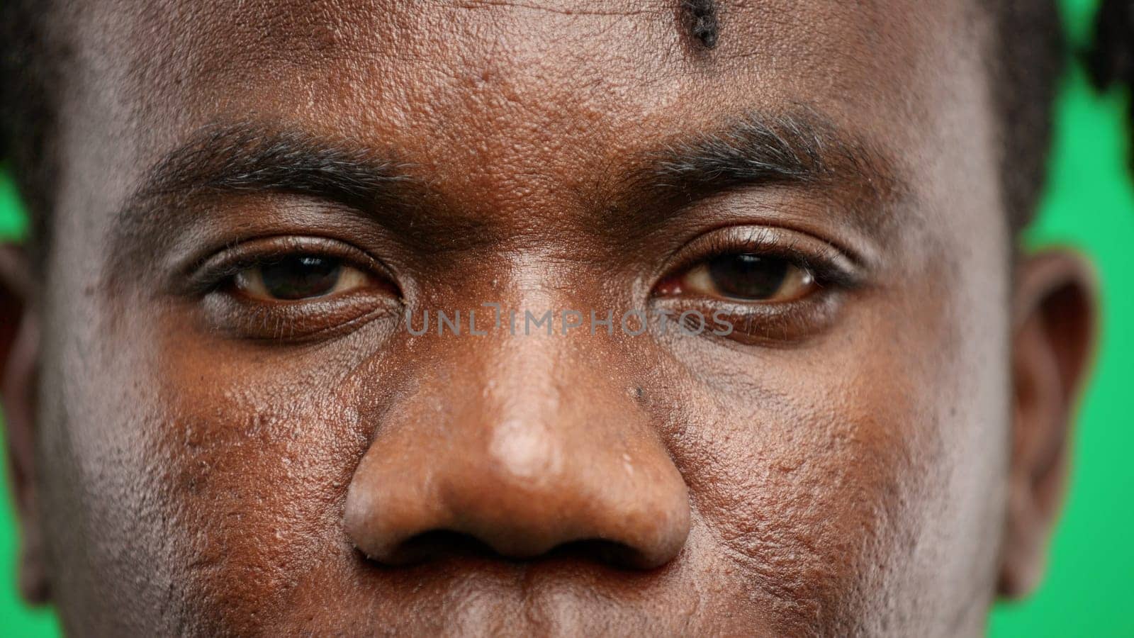 Man's eyes, close-up, on a green background.
