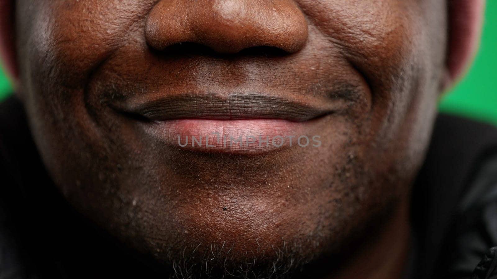 Man's mouth, close-up, on a green background.