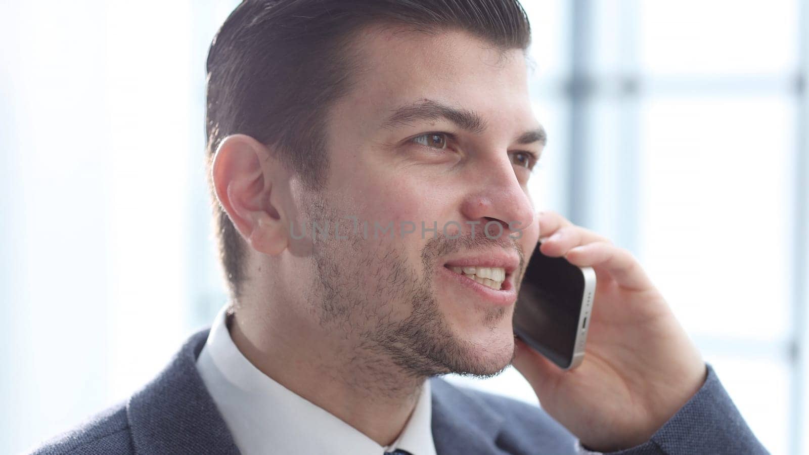 A businessman man in close-up in the office talking on the phone.
