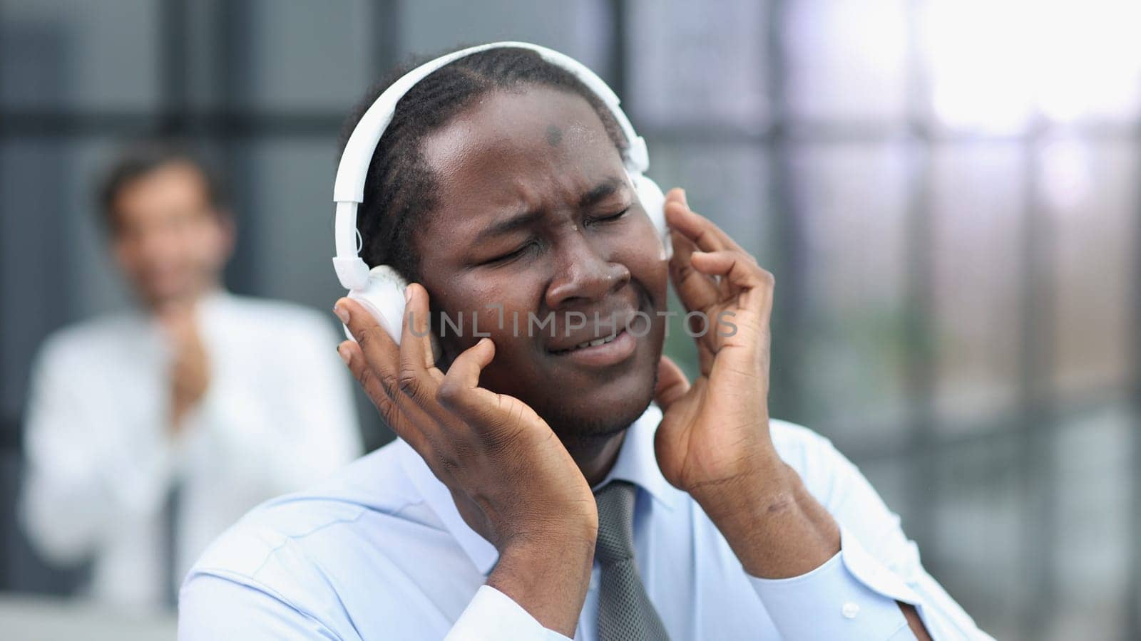 a man at a workplace at a table in front of a computer with headphones listening to music.