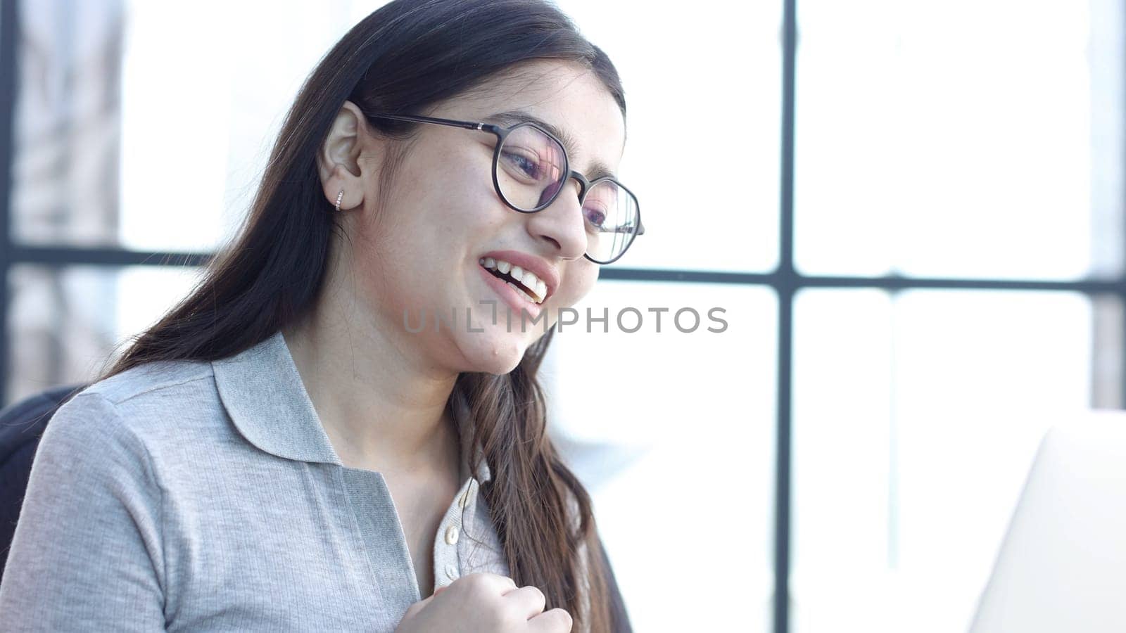 A young woman with glasses in the office is talking on an online video connection.