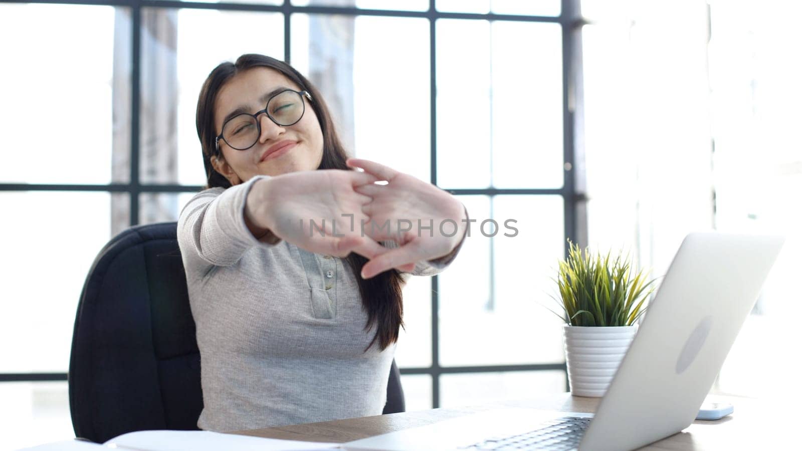 A young woman with glasses in the office is tired working at the computer.