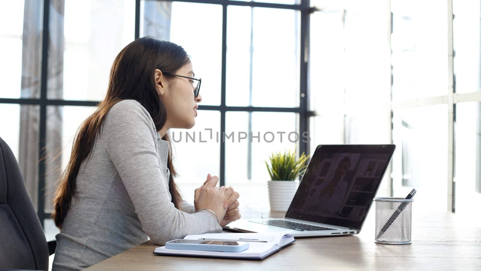 A young woman with glasses in the office is working on a laptop.