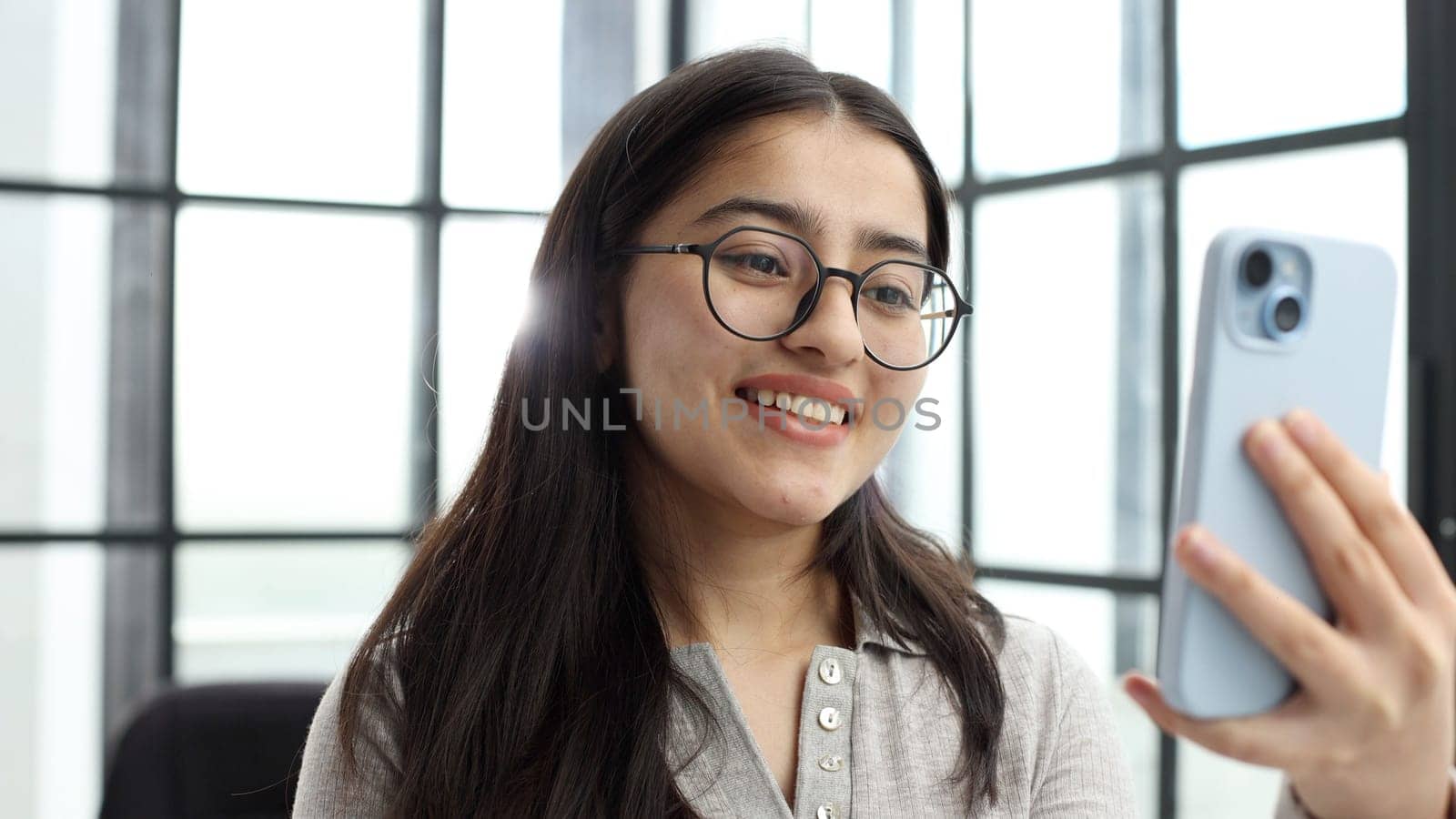 The face of a young successful woman in close-up with glasses in the office.