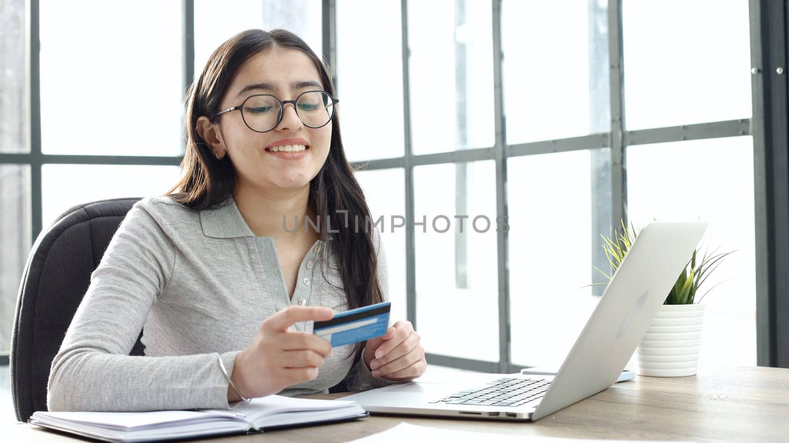 A young woman with glasses checks the card details in close-up.
