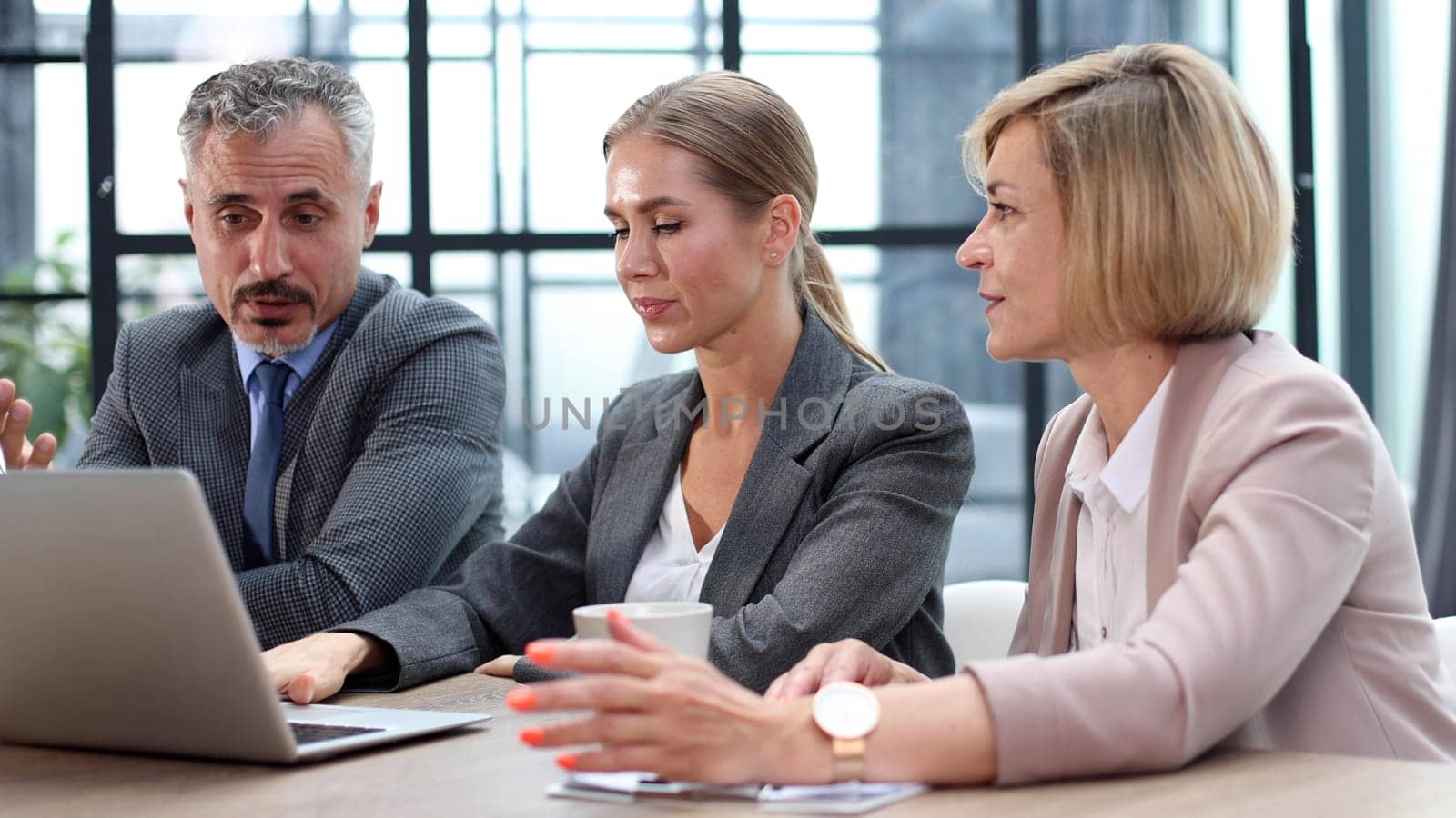 Sits by the table with laptops. Young business people working in the office by Prosto