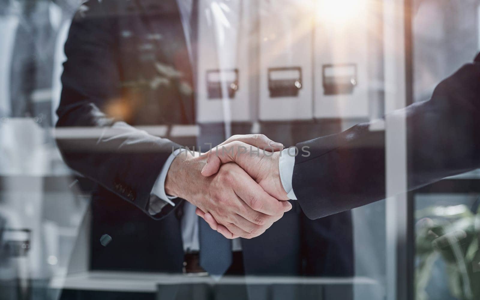 Two business people shaking hands in front of their colleagues