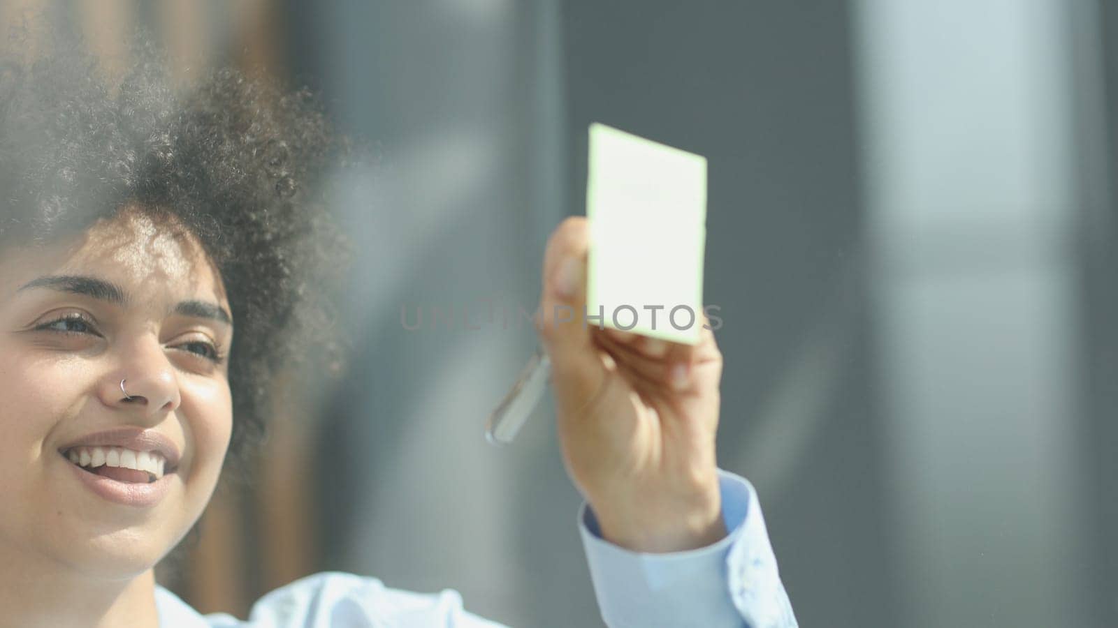 a girl in a modern office behind glass uses sticky notes and makes notes.