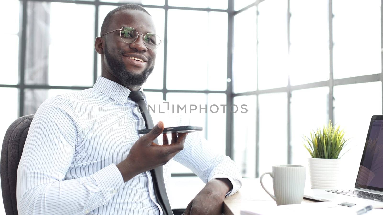 A businessman man in a shirt is talking on the phone in the office in close-up.