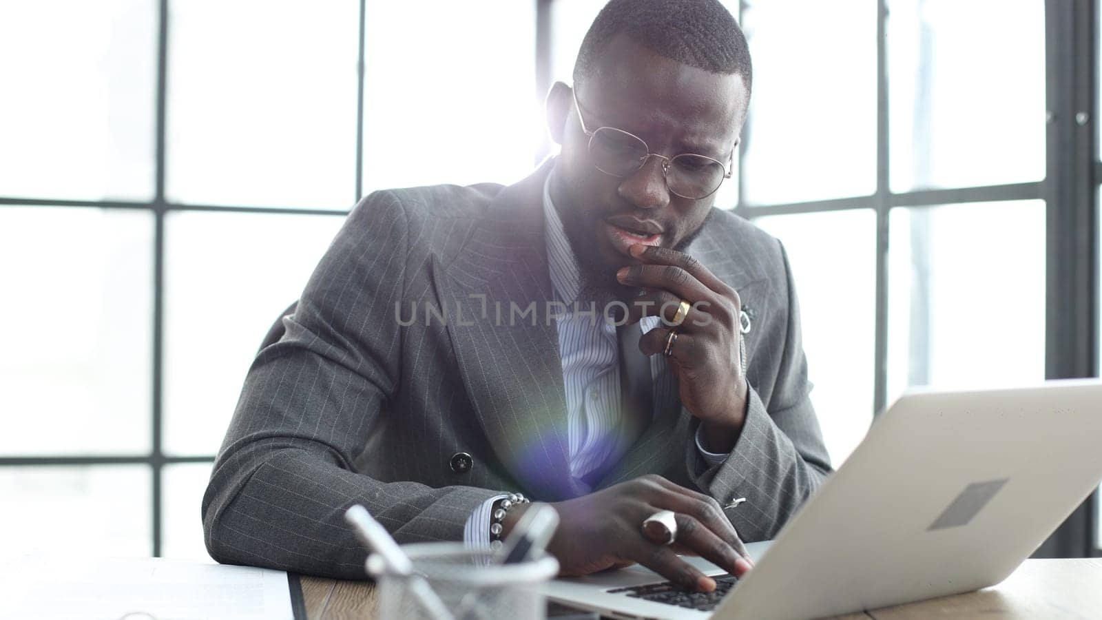 A businessman man in a close-up in a jacket, he works in the office with a laptop by Prosto