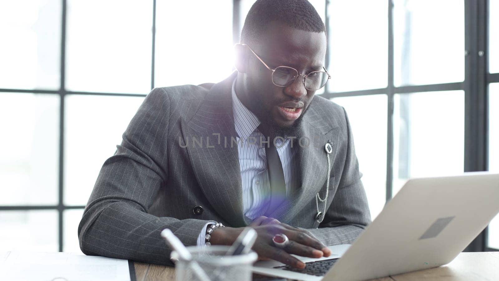 A businessman man in a close-up in a jacket, he works in the office with a laptop.
