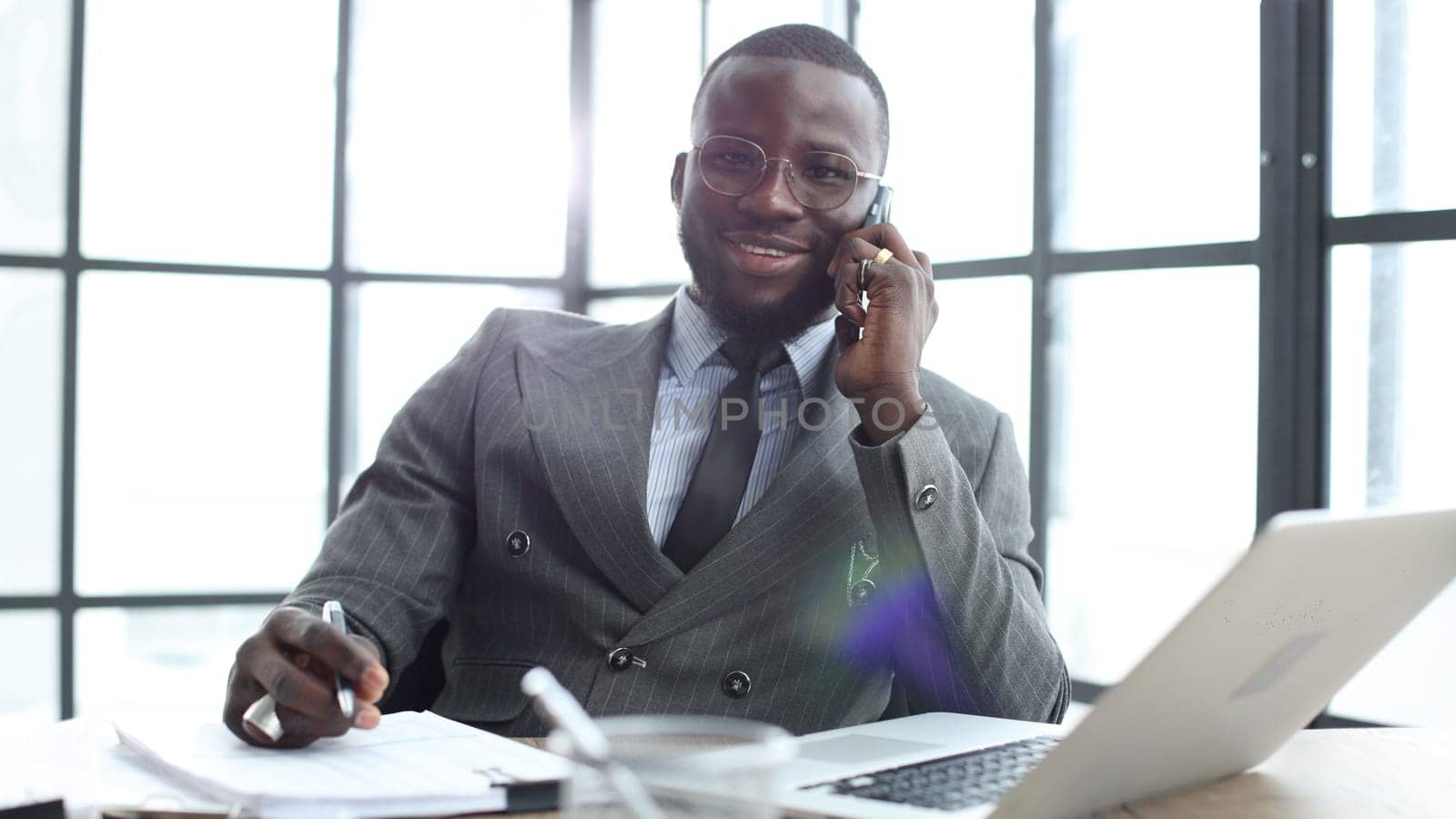 A businessman man in a close-up in a jacket, he is talking on the phone in the office.