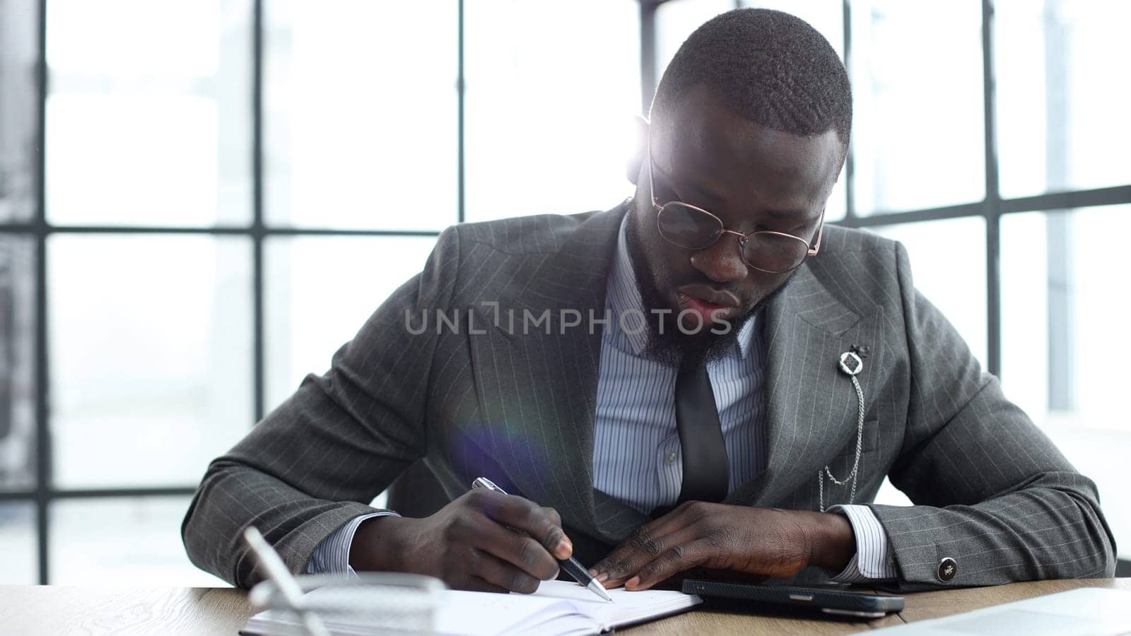 A businessman man in a close-up in a jacket, he writes and checks documents in the office.