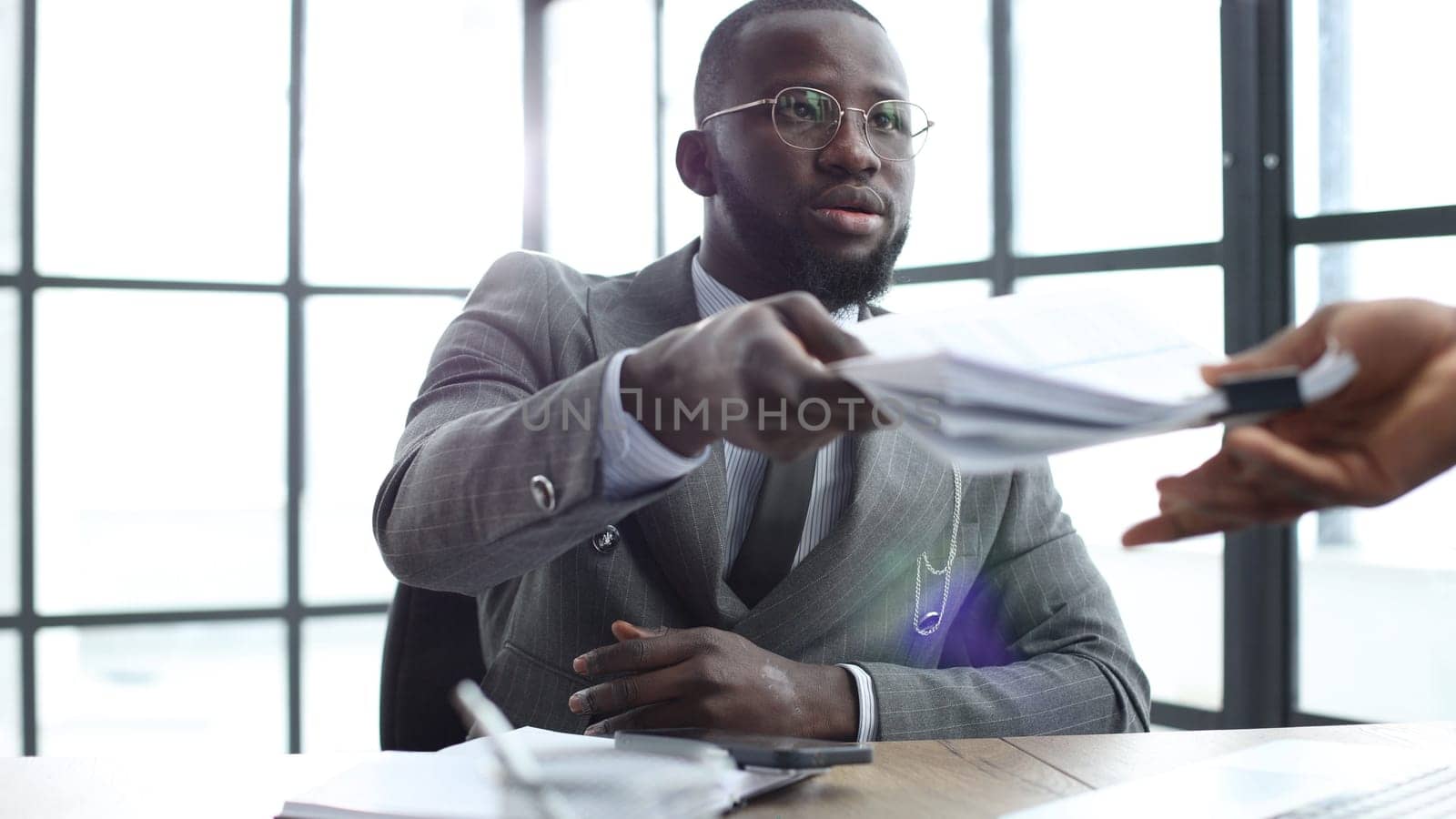 A businessman man in a close-up in a jacket, he is exchanging documents in the office.