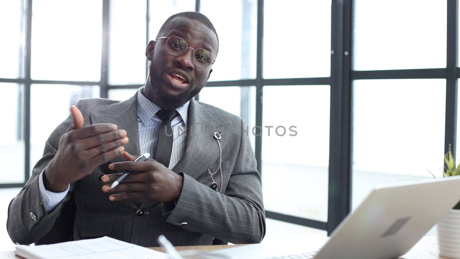 A businessman man in a close-up in a jacket speaks to the camera in the office.