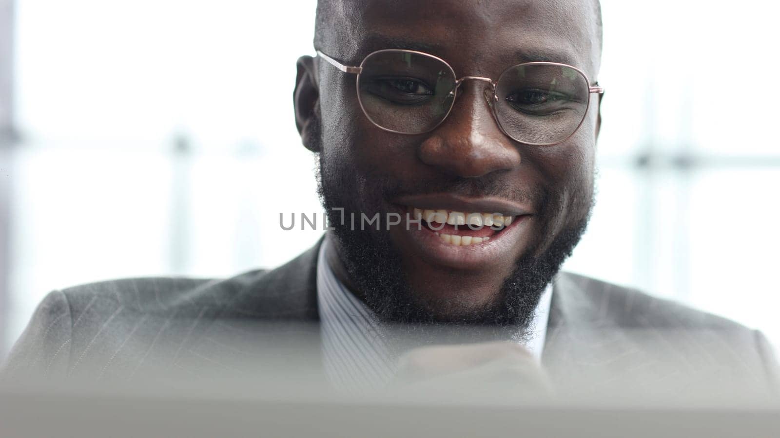 The face of a businessman man in a close-up in a jacket in the office, he is working with a laptop.