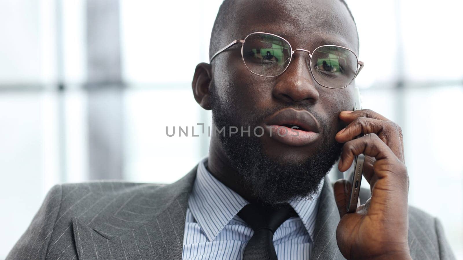 The face of a businessman man in a close-up in a jacket in the office talking on the phone.