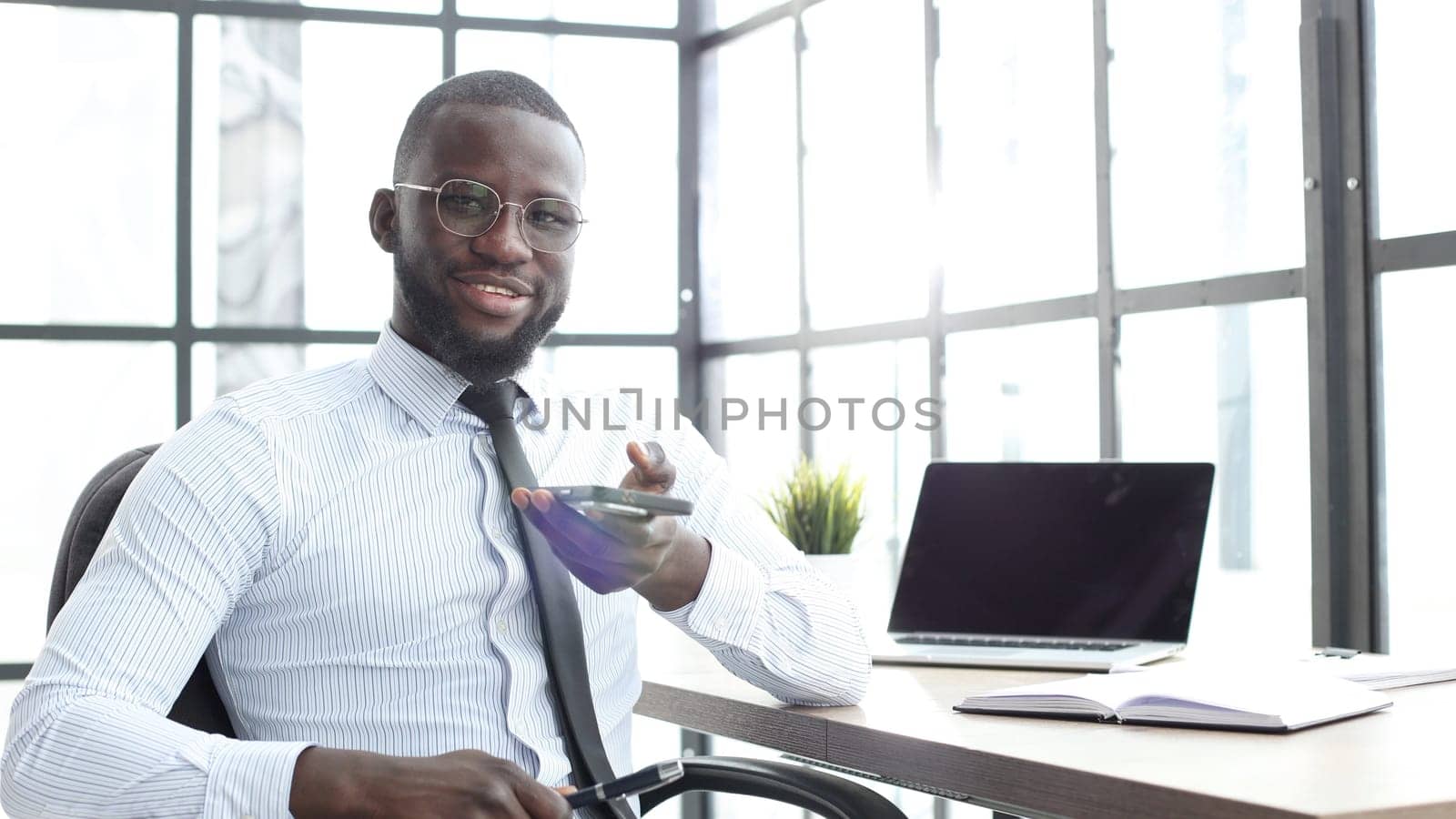 A businessman man in close-up in a shirt in the office talking on the phone.