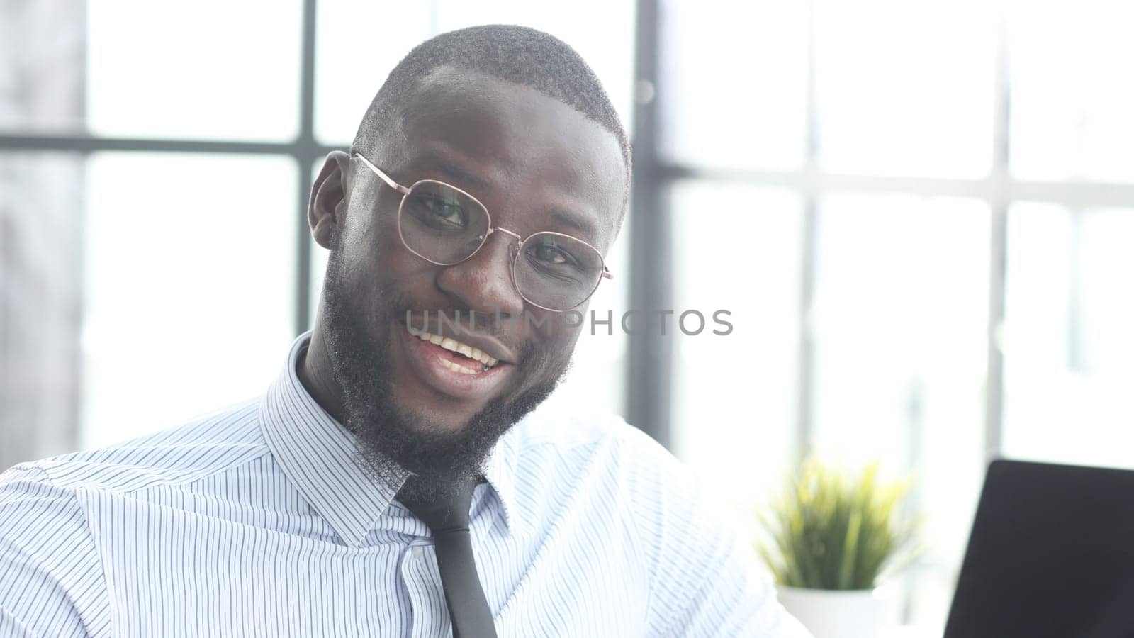 The face of a businessman man in close-up in the office, he looks at the camera.