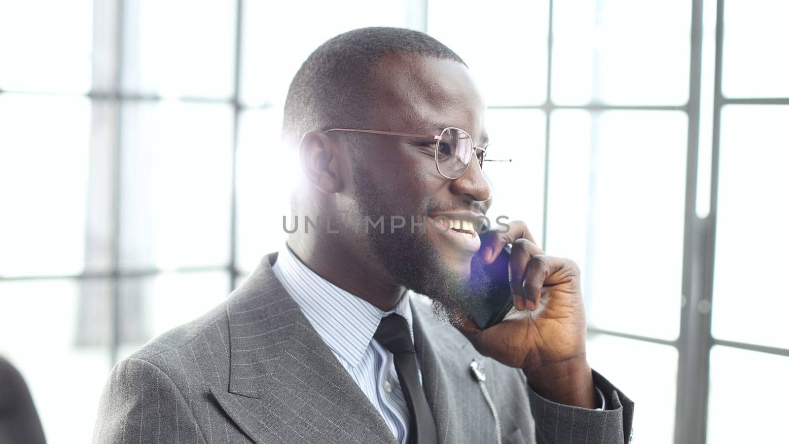 The face of a businessman man in a jacket is a close-up in the office, he is talking on the phone by Prosto