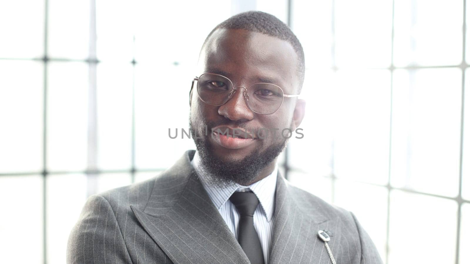 The face of a businessman man in a jacket is a close-up in the office, he looks at the camera.