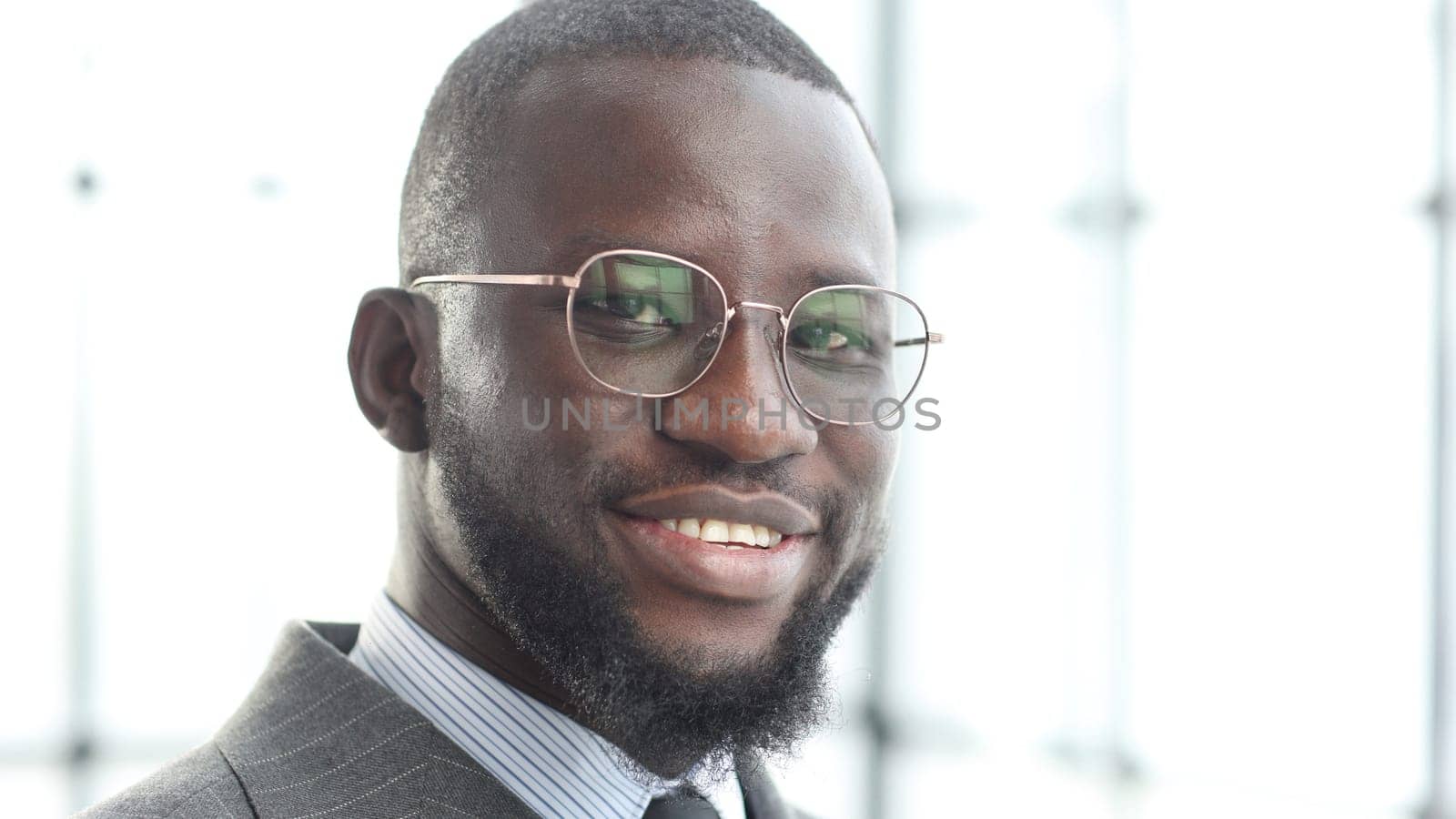 The face of a businessman man in a jacket is a close-up in the office, he looks at the camera.