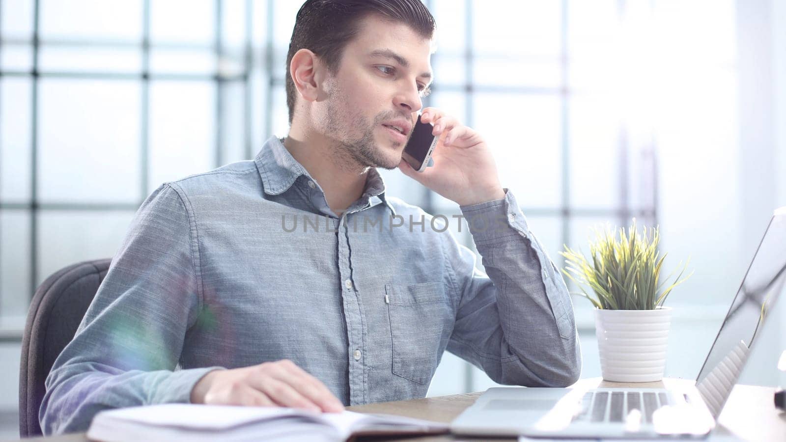 A male office worker is talking on the phone in close-up.