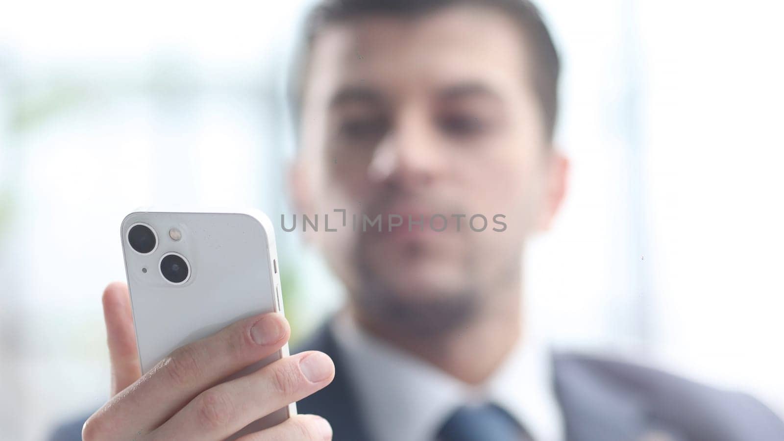 A male businessman uses a phone in close-up.