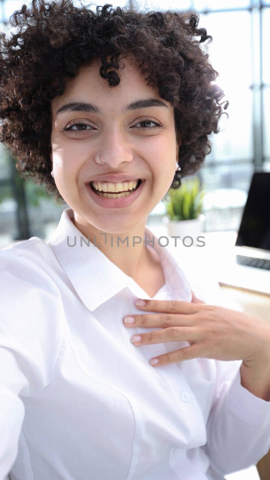 Image of young beautiful joyful woman smiling while working with laptop in office