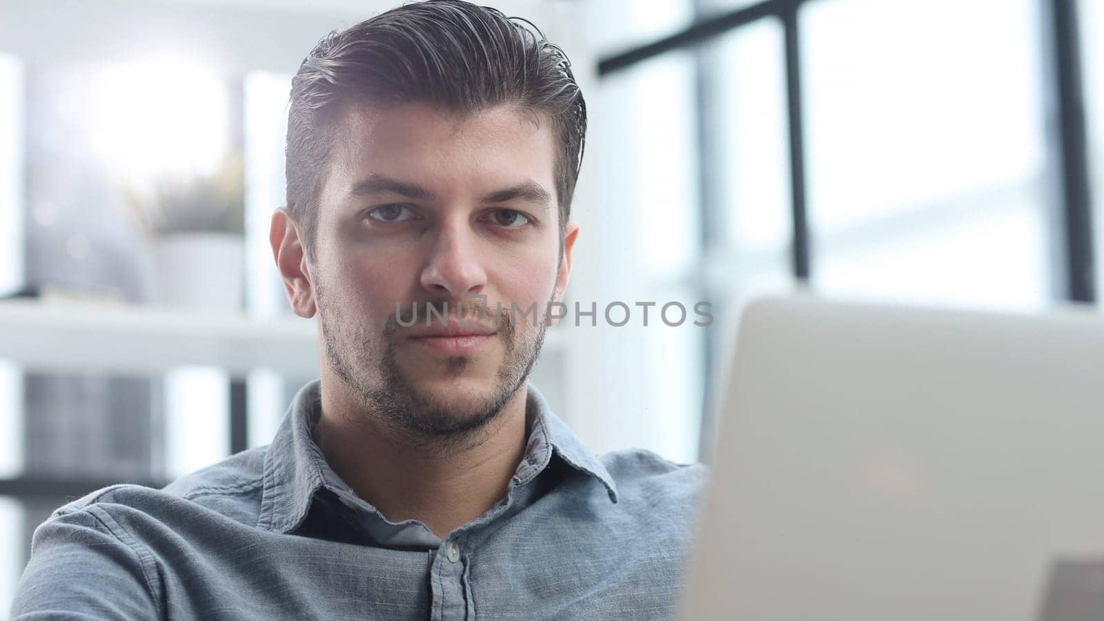The man's face is in close-up, he is using a laptop.