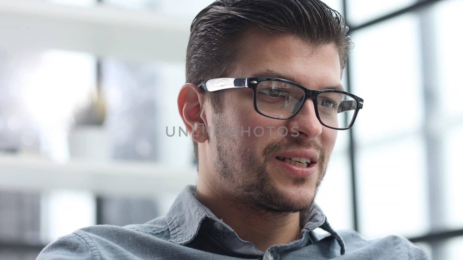 The man's face is in close-up with glasses, he looks thoughtfully away.