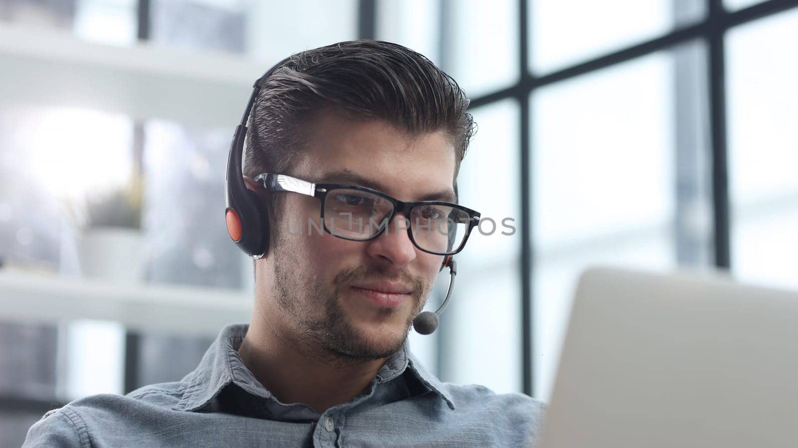 A man with headphones in close-up using a laptop.