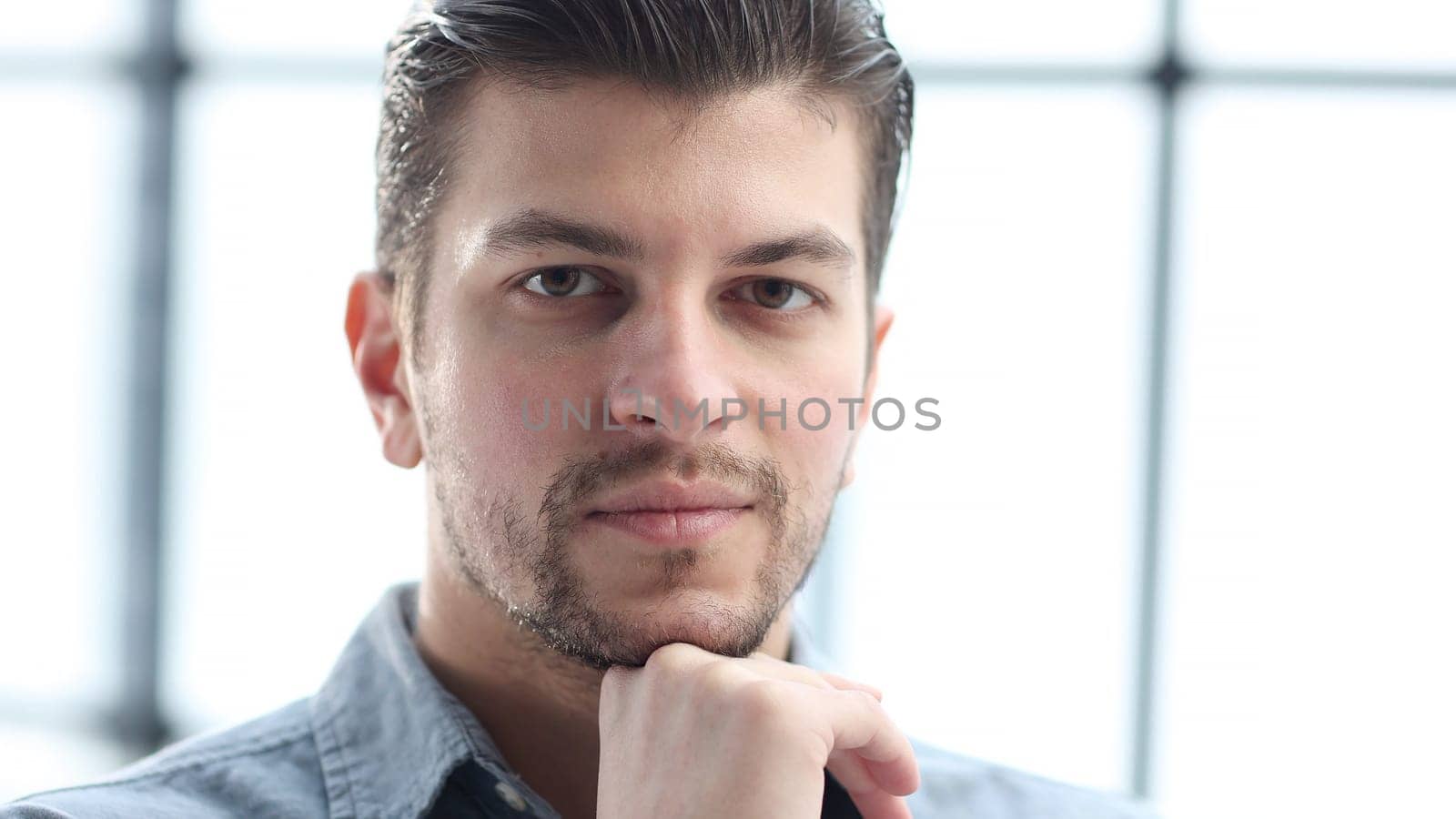 The man's face in close-up looks thoughtfully at the camera.