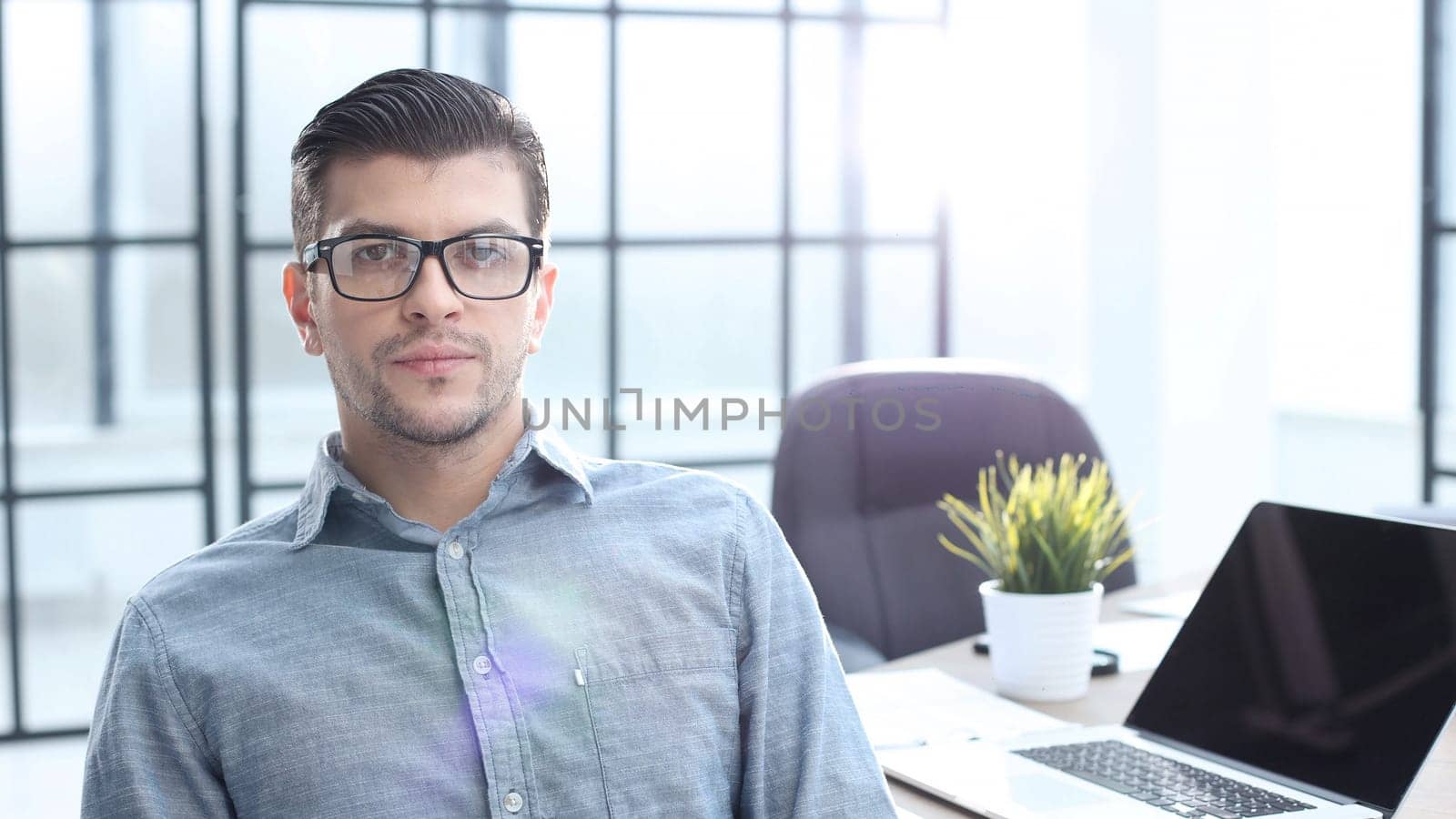 A male office worker looks at the camera in close-up.