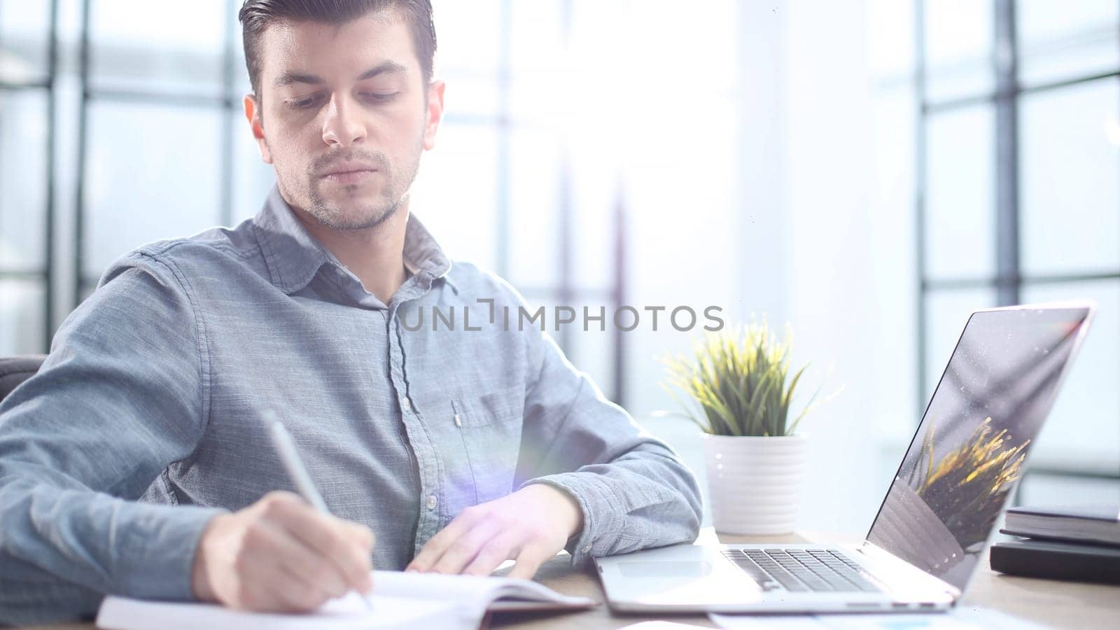 Male office worker in close-up working on a laptop.
