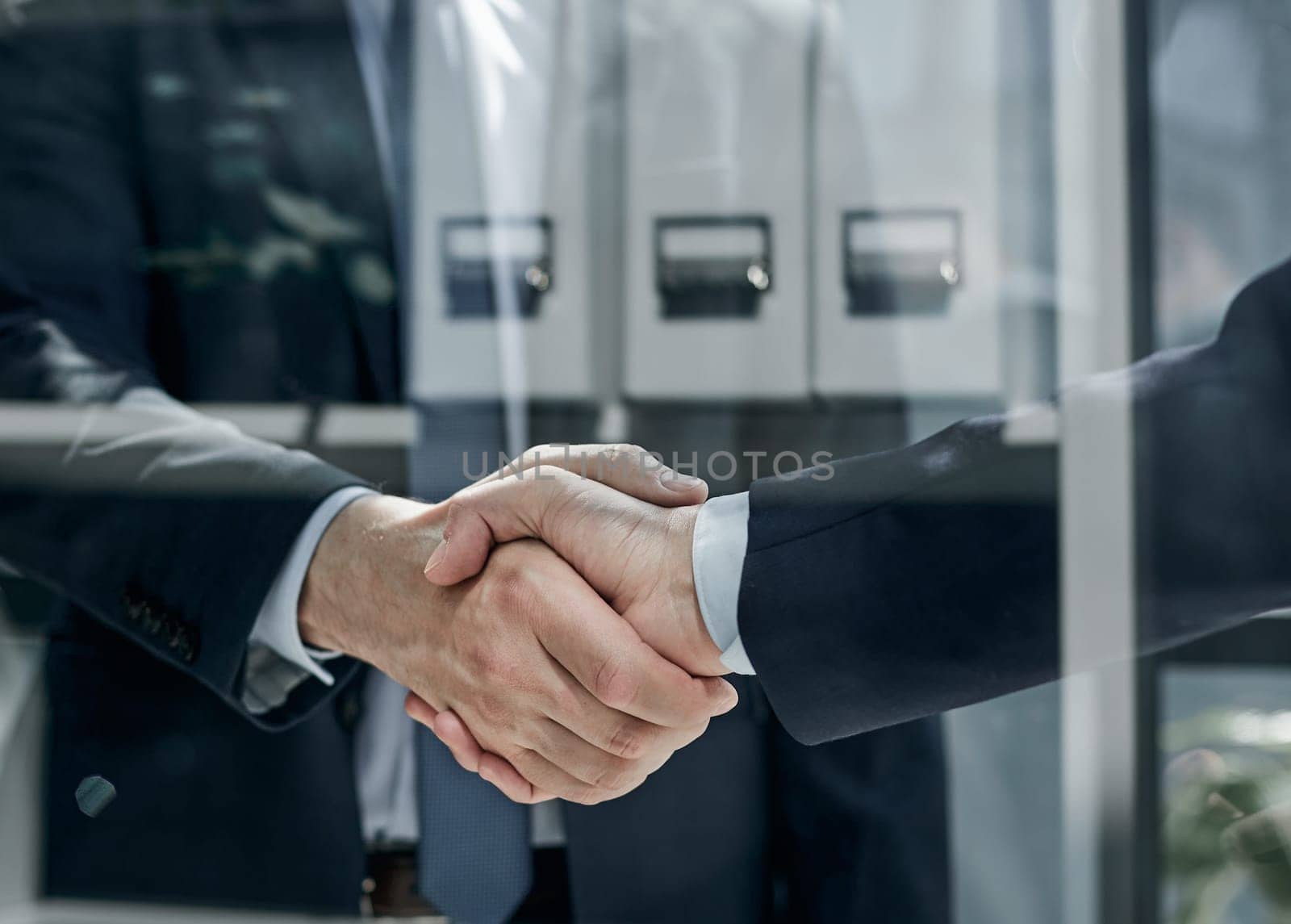 Two business people shaking hands in front of their colleagues