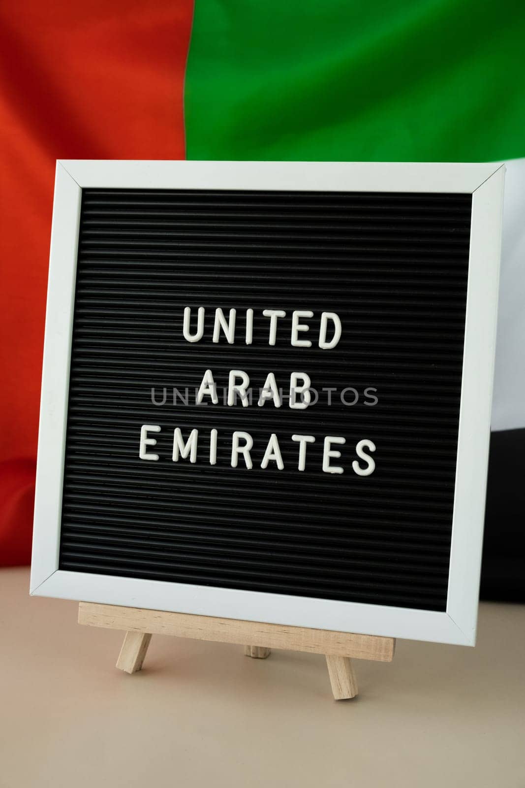 Text UNITED ARAB EMIRATES on background waving flag of UAE. National holiday, Independence Commemoration Day Muslim, congratulations. Arabian holidays. Advertisement of Dubai celebration