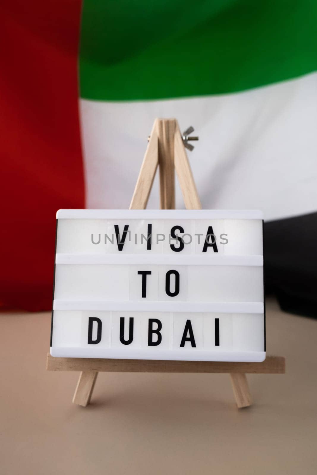 Lightbox with text VISA TO DUBAI on background of waving UAE flag made from silk. United Arab Emirates flag with concept of tourism and traveling. Inviting greeting card, advertisement. Dubai welcoming card