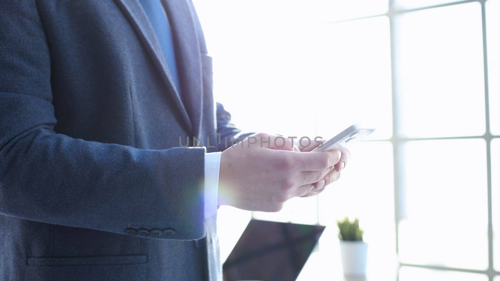 A businessman man in a close-up in a jacket uses a phone.