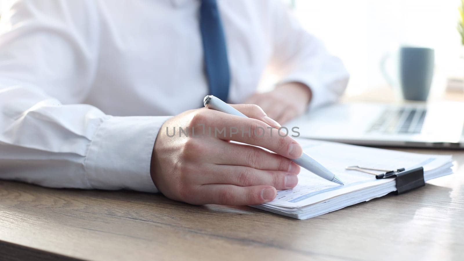 A businessman man in close-up in a shirt checks documents.