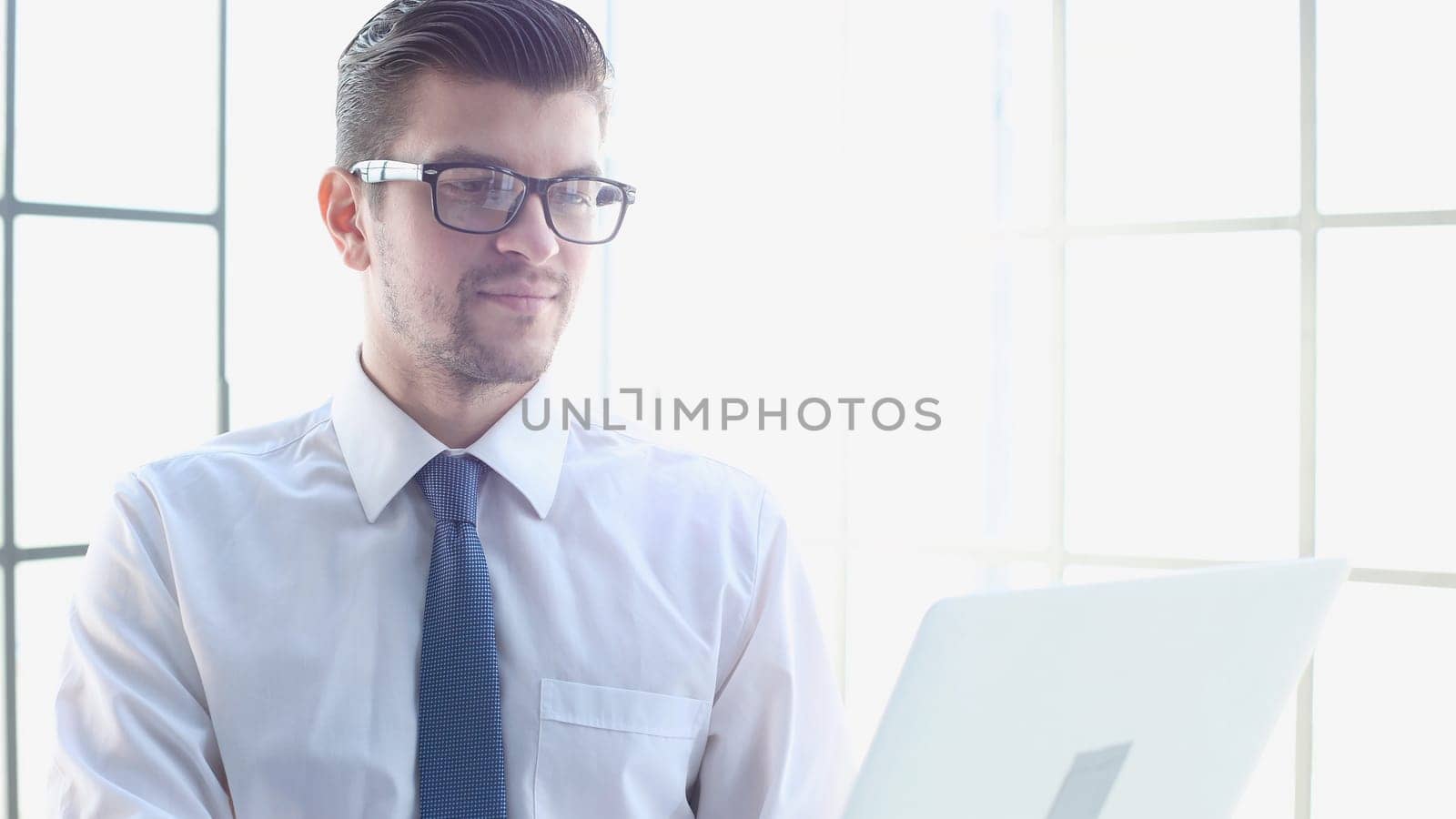 Male businessman in close-up in shirt using laptop.