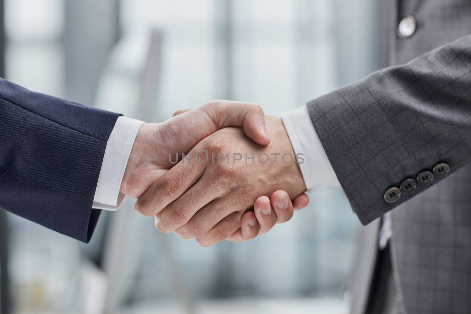 Building a strong business network. two businessmen shaking hands in a modern office. by Prosto
