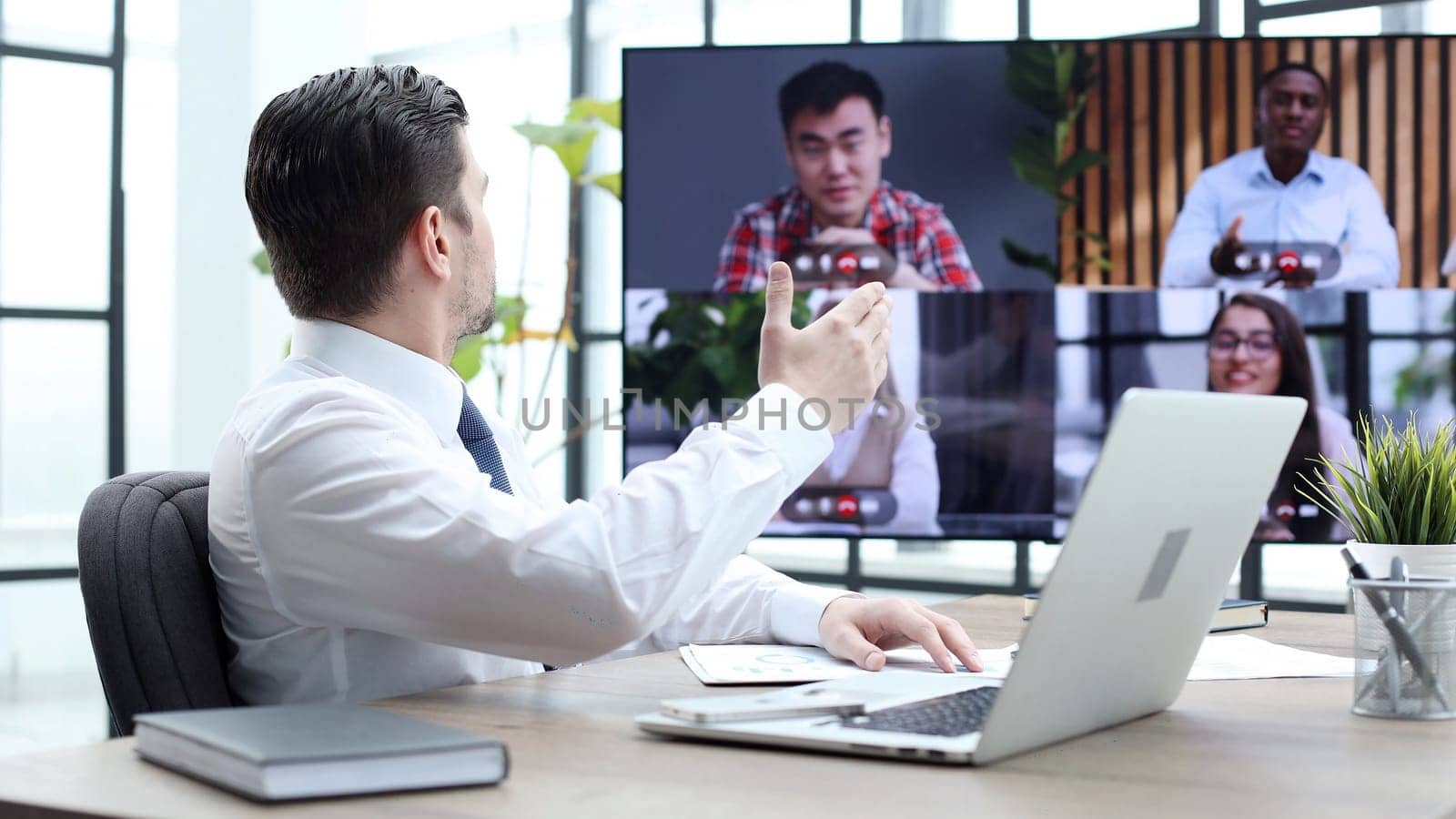 A male businessman is talking to colleagues at an online meeting by Prosto