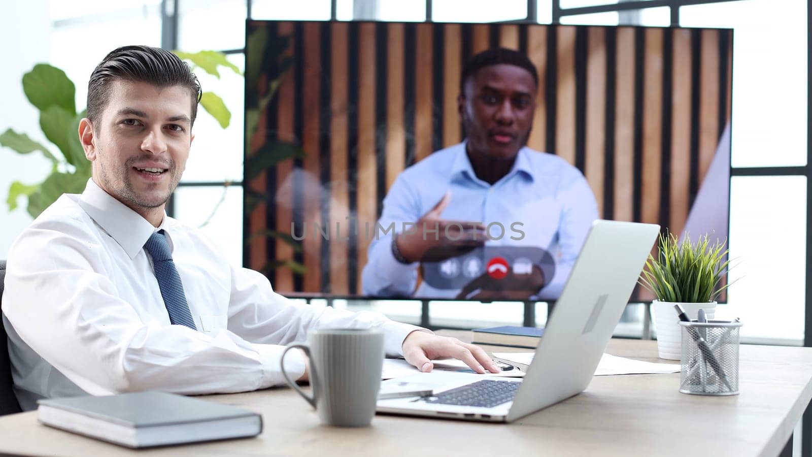 A male businessman is talking to colleagues at an online meeting.