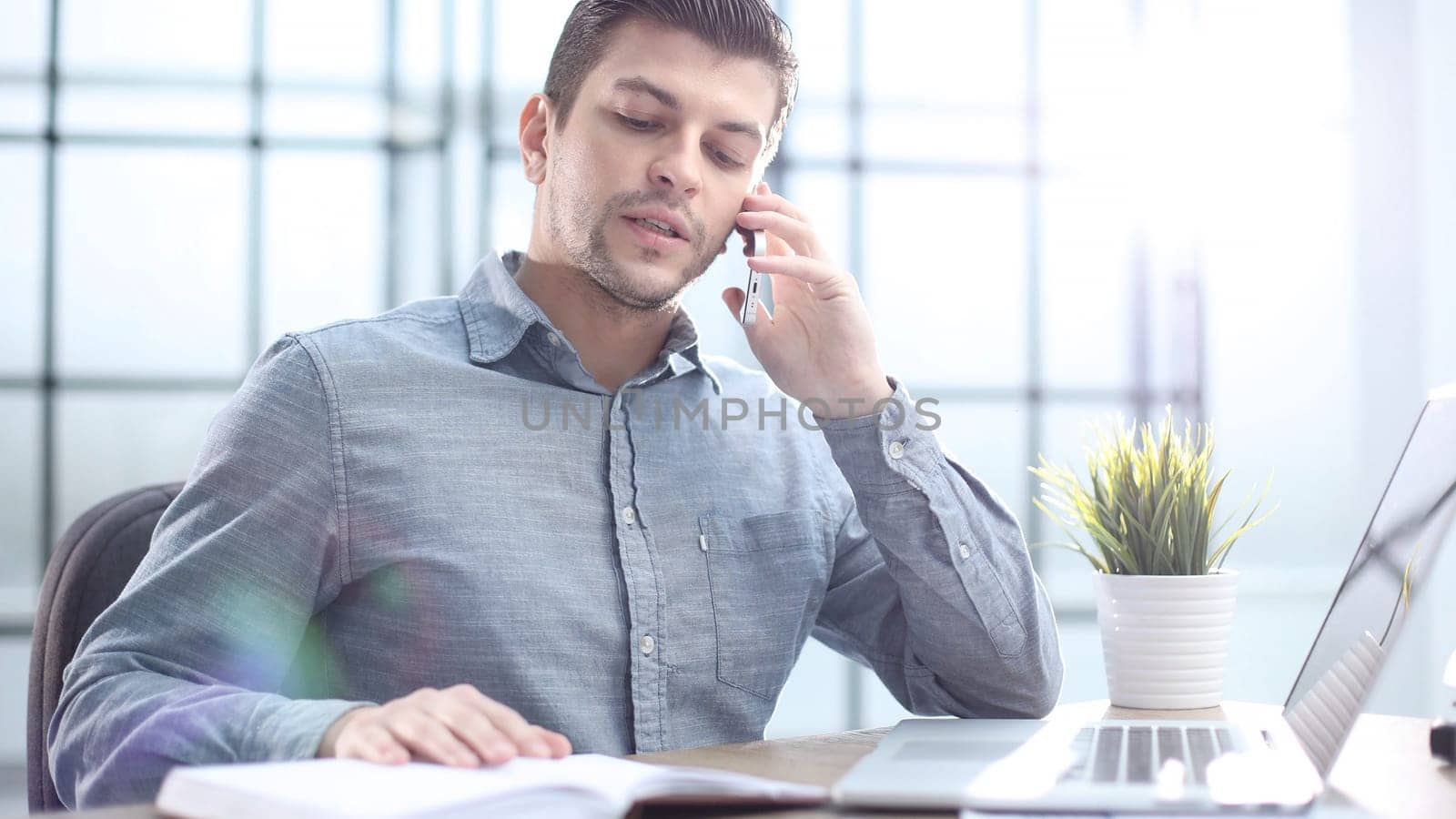 A male office worker is talking on the phone in close-up.