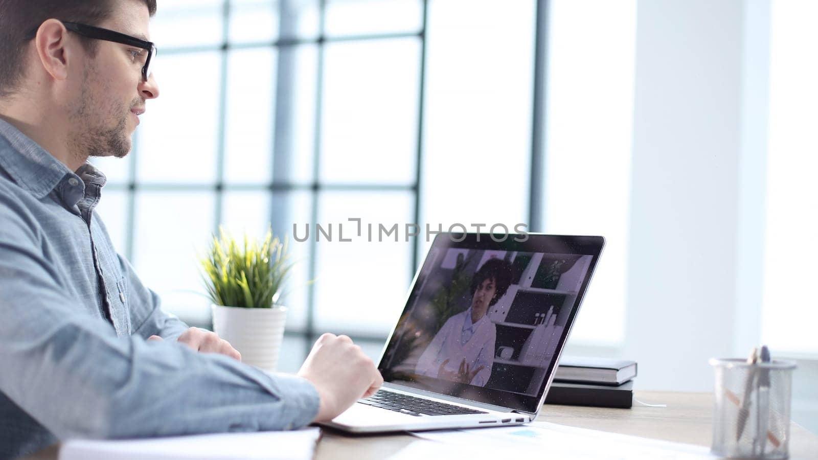 A male office worker at an online meeting with colleagues by Prosto